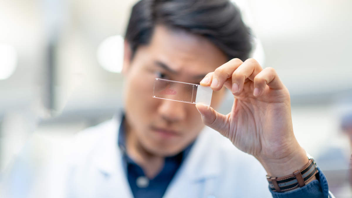 man looking at microscope slide