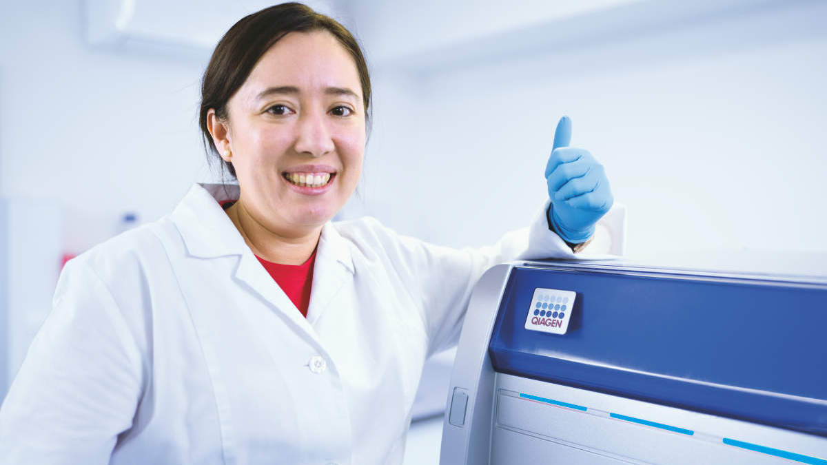 woman in lab standing next to QIAcuity instrument