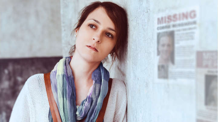 Sad woman standing next to missing person poster