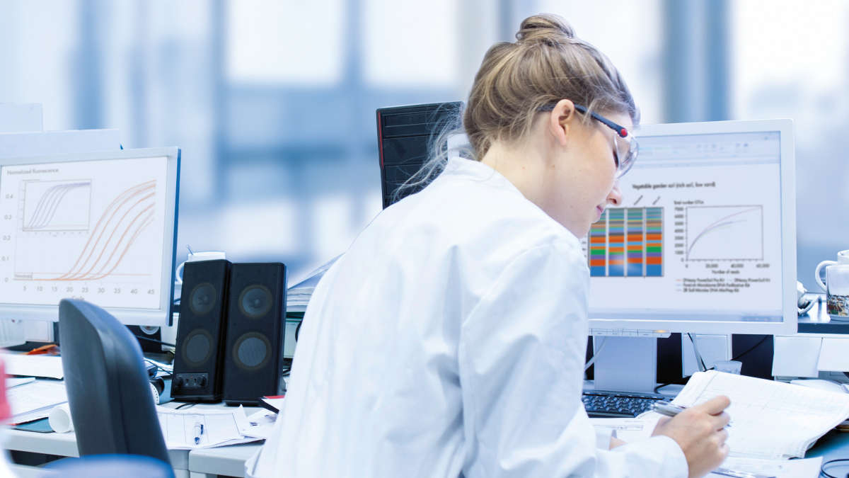 woman working in lab infront of a computer with graphs