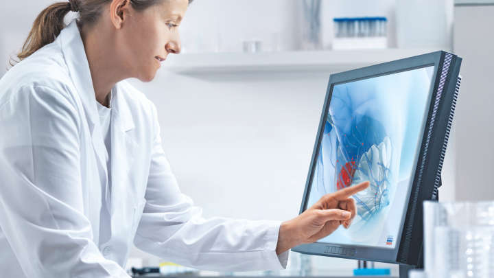 QIAseq Multimodal BRCA, female scientist working on a computer, breast cancer 3D image on screen