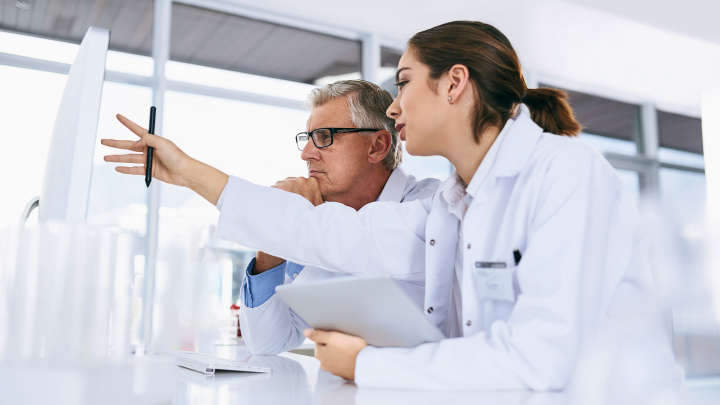 two scientist in front of a monitor