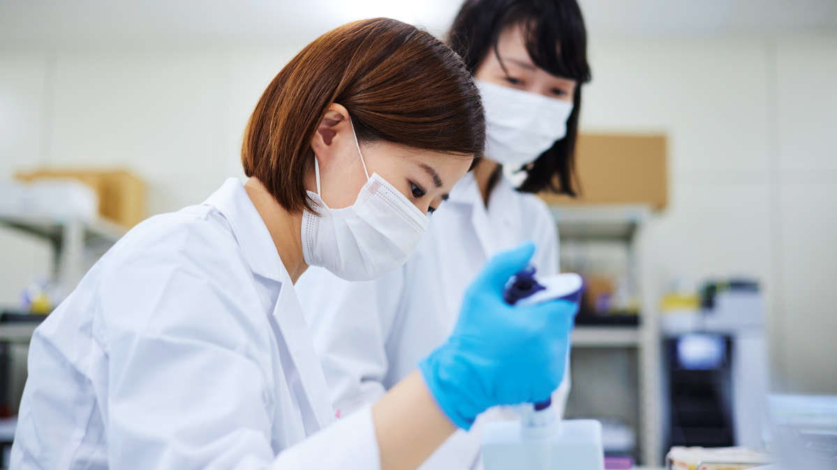 Two scientists working in a laboratory, focused on pipetting, Clinical Genomics