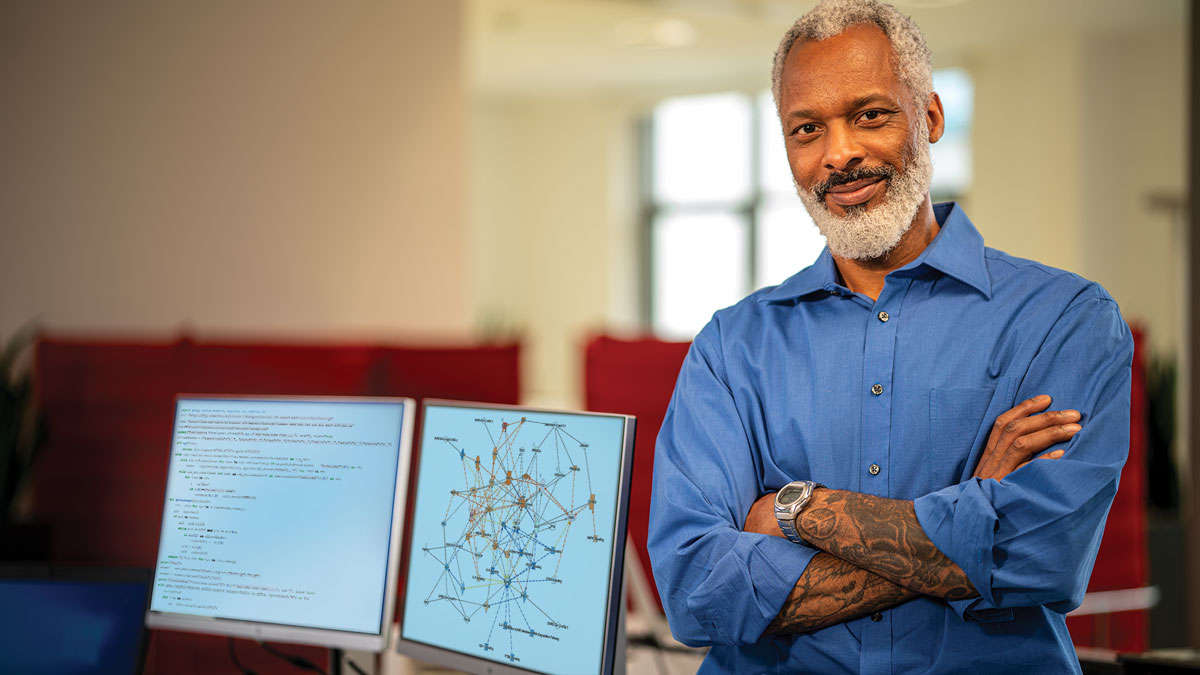 QDI, PKB, QDI Data Scientist in front of two computer screens in an office setting