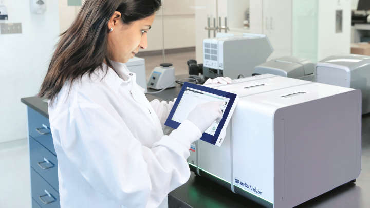 Woman in a lab working with QIAstat-Dx