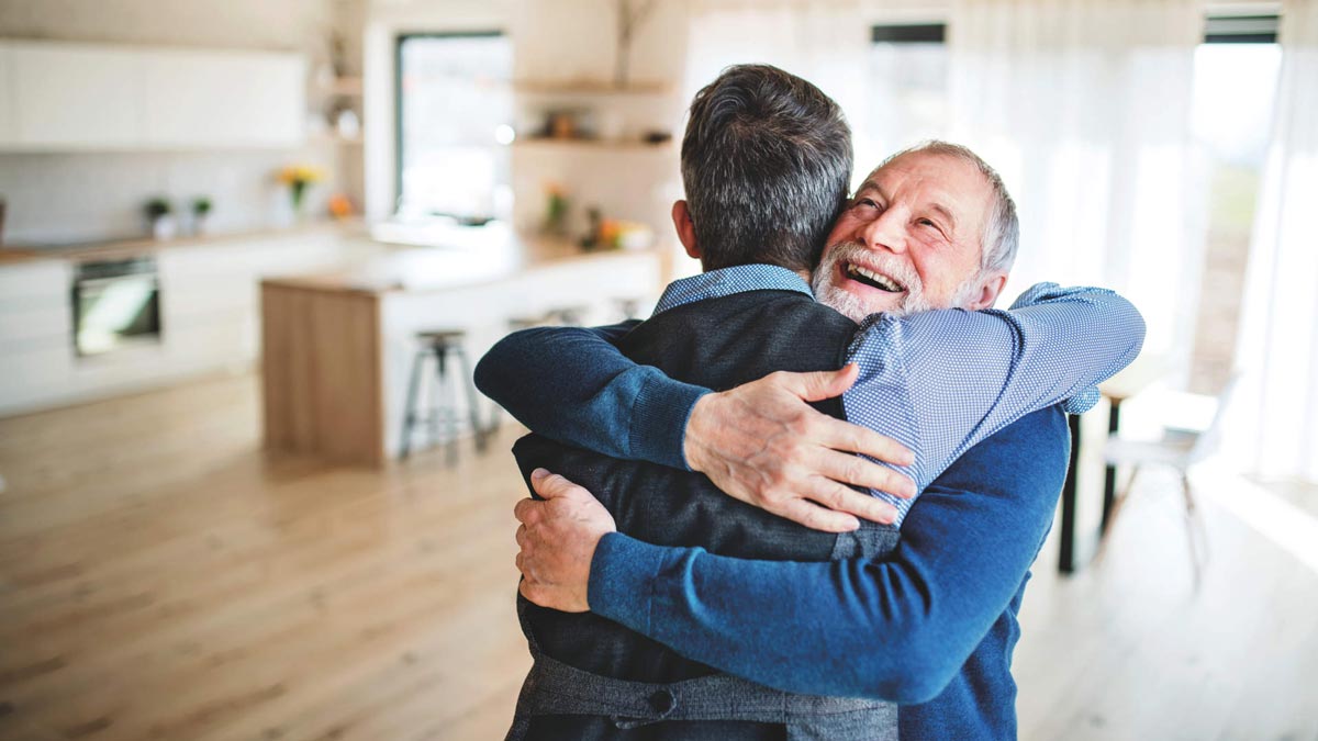 An Adult Hipster Son And Senior Father Indoors At Home, Hugging