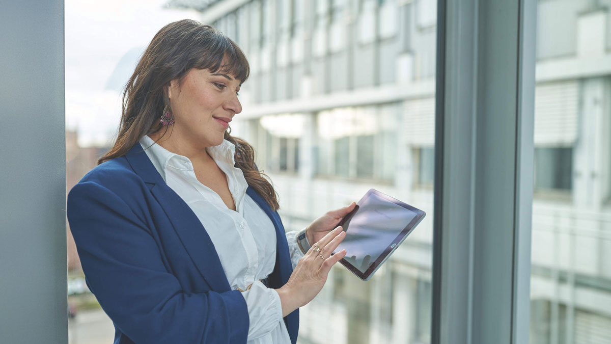 A female person holding a tablet with QIAstat-Dx, QIAspehere app