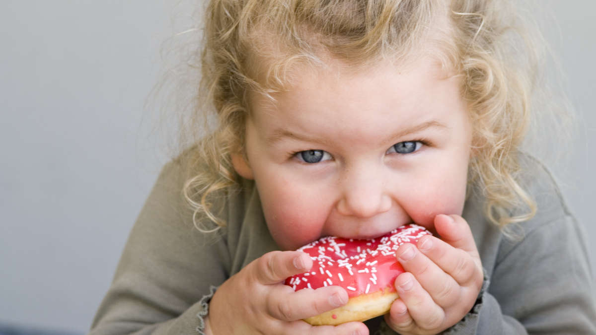 a little girl eating a donut