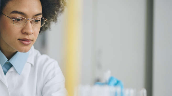 Enterprise Genomics Solutions, scientist taking notes, looking at a tube, result